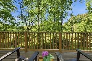 Une terrasse en bois dotée d’une rambarde, qui offre une vue sur une zone boisée.