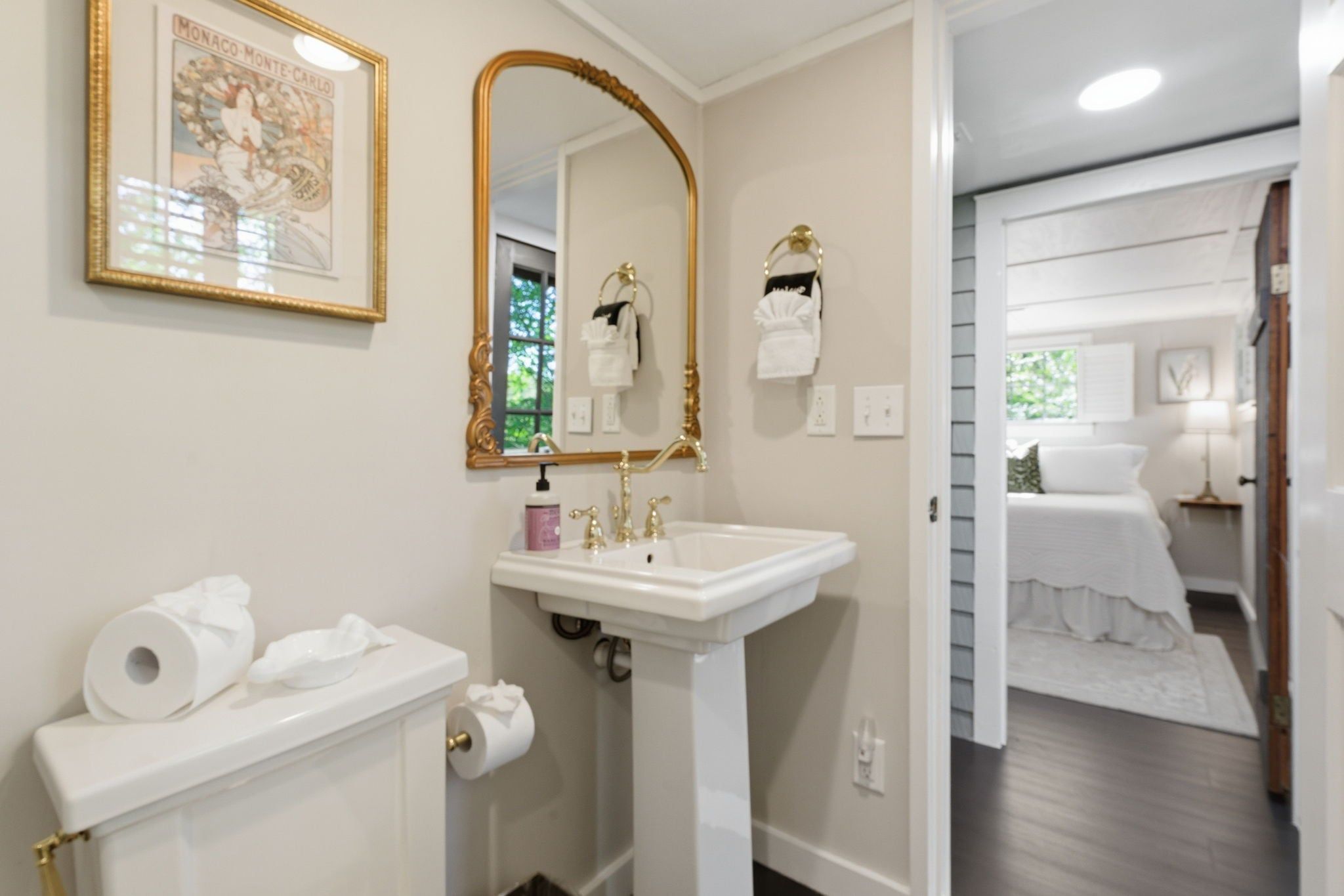 A bathroom with a toilet, sink, and a large mirror.