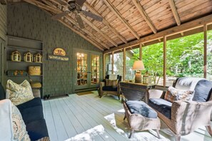 A cozy room with wicker furniture, a ceiling fan, and large windows offering a view of greenery. - The Hideaway Of Horse Cove (Highlands)