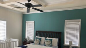 A bedroom with a bed, a ceiling fan, two bedside tables, a nightstand, and a crib. - Charming 2-bedroom house with WiFi, AC in delightful Key Largo (Key Largo)