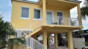 A two-story yellow building with white railings and a covered balcony. - Charming 2-bedroom house with WiFi, AC in delightful Key Largo (Key Largo)