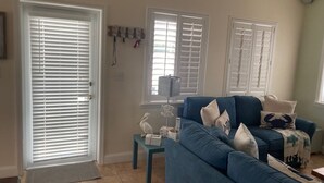 A living room with a blue sofa, a small table, and a door with white blinds. - Charming 2-bedroom house with WiFi, AC in delightful Key Largo (Key Largo)