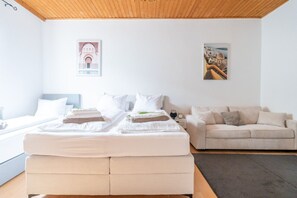 A modern hotel room with a large bed, a sofa, and two wall-mounted artworks.