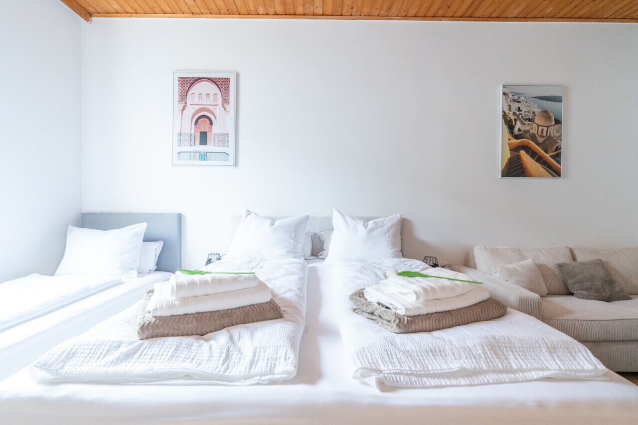 Ein Hotelzimmer mit zwei Betten, weißer Bettwäsche und Bildern an den Wänden.