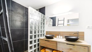 A modern bathroom with a large mirror, two sinks, and a towel rack. - Luxury studio, oasis of peace, centrally located close to most beautiful beaches (Sint Willibrordus)