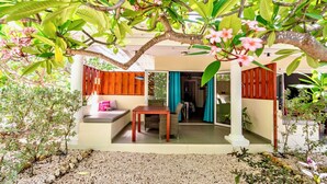 A covered outdoor seating area with a table and chairs, surrounded by lush greenery and flowering plants. - Luxury studio, oasis of peace, centrally located close to most beautiful beaches (Sint Willibrordus)