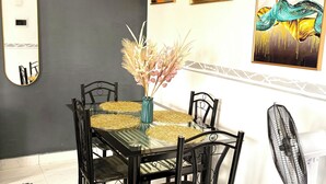 Un coin repas avec une table en verre, des chaises noires et un vase décoratif.