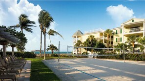 Un hotel frente a la playa con piscina, palmeras y vistas al océano.