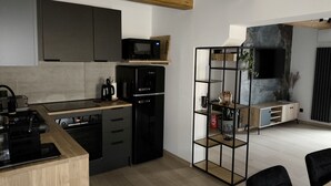 A modern kitchen with a built-in microwave, a black refrigerator, and a wooden dining table with chairs. - Apartamenty Rynek Szamotuły (Szamotuly)
