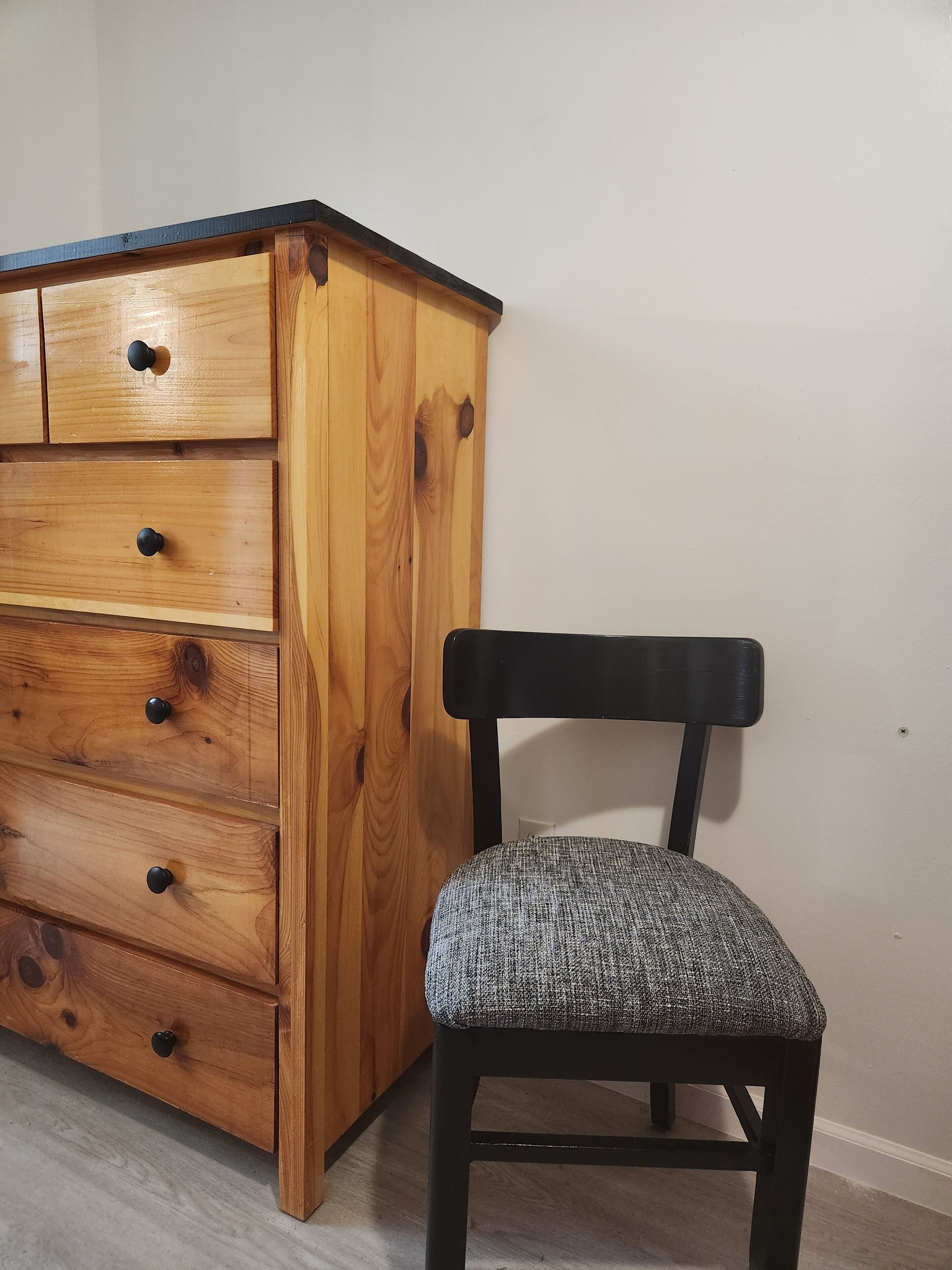 Een houten dressoir met meerdere lades en een stoel met een geweven zitvlak.