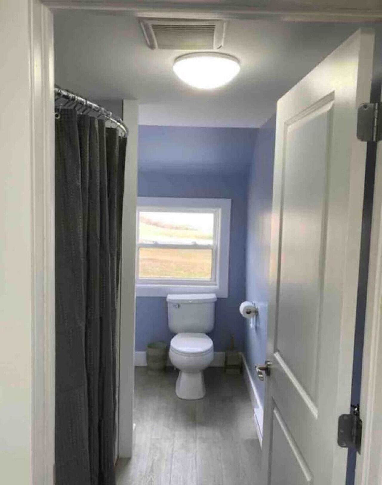 Une salle de bain avec des toilettes, une fenêtre et un rideau de douche.