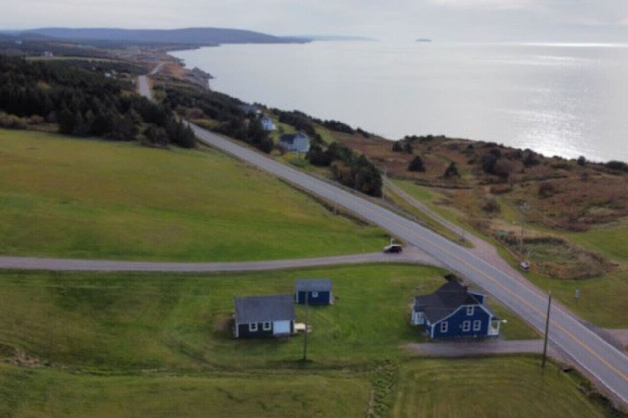 Eine Küstenstraße mit Häusern und einem Gewässer im Hintergrund.
