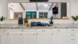 Una cocina moderna con armarios blancos, encimera de granito y campana extractora negra.