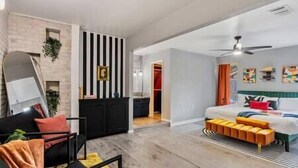 Habitación de hotel moderna con cama, escritorio y silla. Hay un armario y una puerta que da a otra habitación.