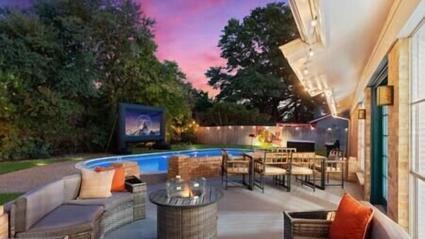 Un espacio al aire libre con piscina, muebles de mimbre y una pantalla de televisión.