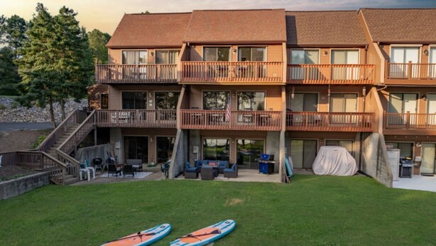 Un edificio de varios pisos con balcones, mobiliario exterior y kayaks en el patio.