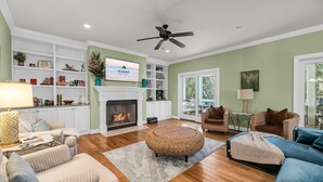 Una sala de estar con chimenea, televisor y ventilador de techo.