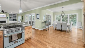 Una cocina amplia con una estufa grande, armarios de madera y un comedor con sillas y una mesa.