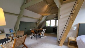 Habitació d'estil loft amb zona de menjador, cuina i espai per dormir.