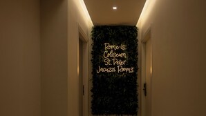 A hallway with a neon sign reading "Rome is: Colseum St. Peter Jaazzi Rooms" on a wall. - Jacuzzi Rooms Vatican Museum (Rome)