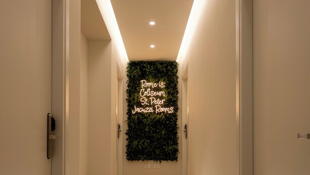 A hallway with a neon sign reading "Rome: Colosseum St. Peter's Basilica Rooms." - Jacuzzi Rooms Vatican Museum (Rome)