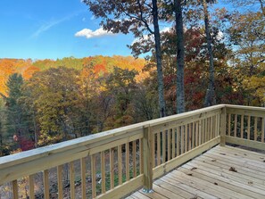 A wooden deck with a view of a forested area with autumn foliage.