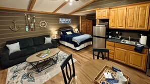 A cozy cabin-style room with a bed, a sofa, a dining table, and a kitchenette. - Modern luxury- Rustic Charm (Afton)