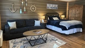 A cozy room with a bed, a sofa, a coffee table, and nautical decor including an anchor and a ship's wheel. - Modern luxury- Rustic Charm (Afton)
