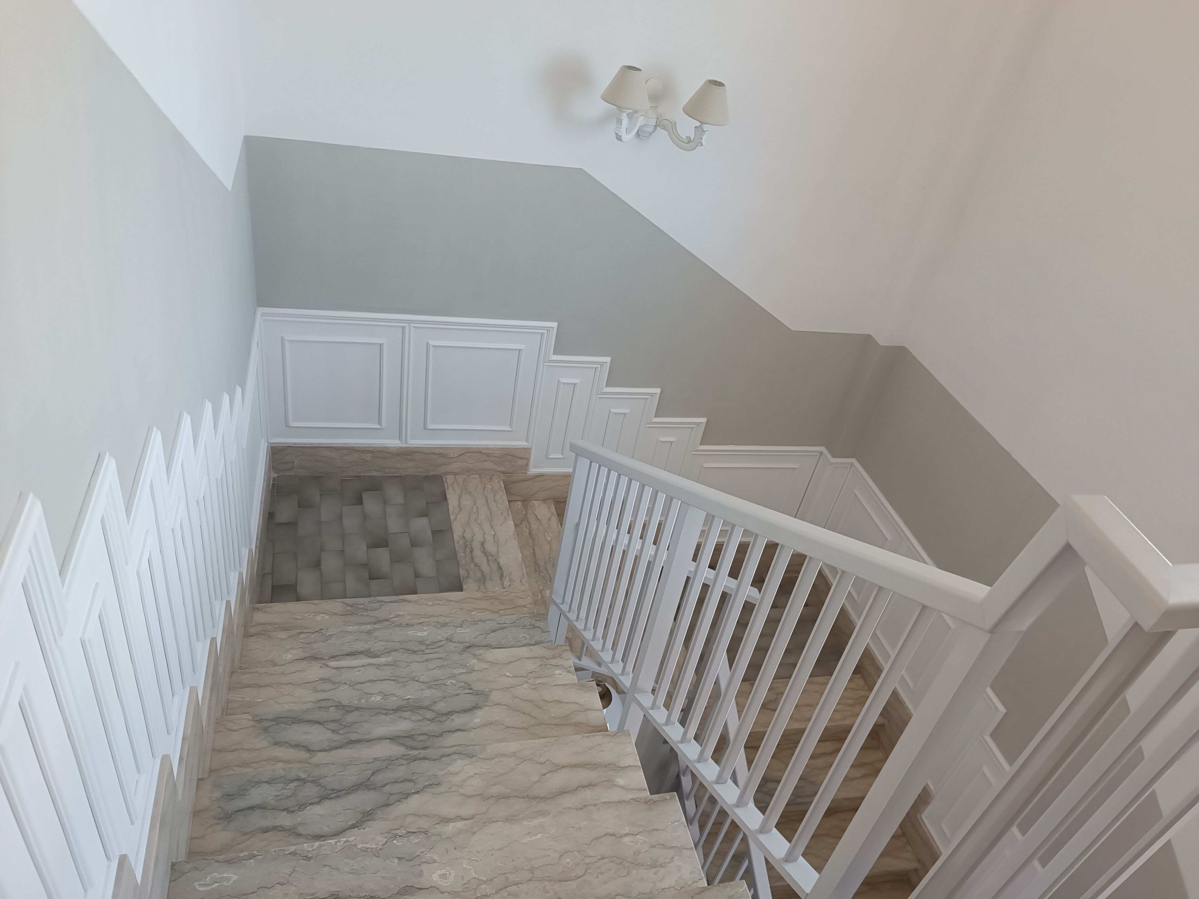 A staircase with white railings and a marble floor.