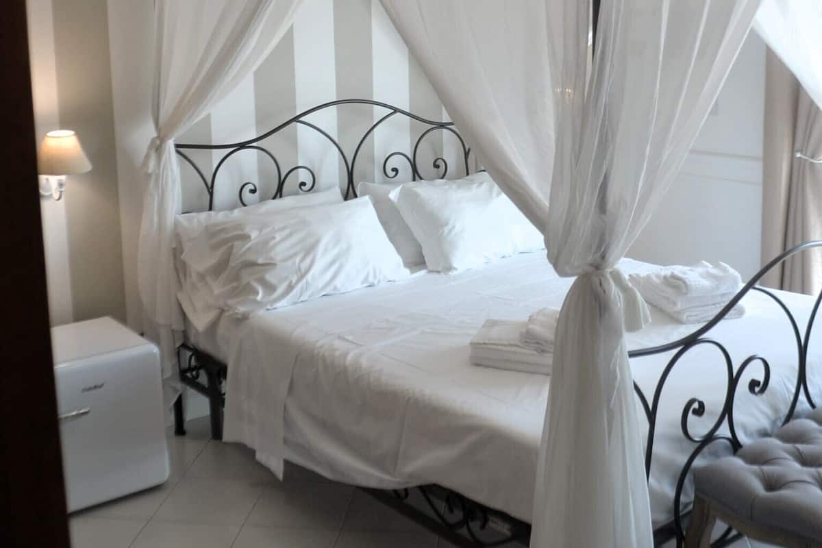 A four-poster bed with a canopy, a bedside table, and a bench.