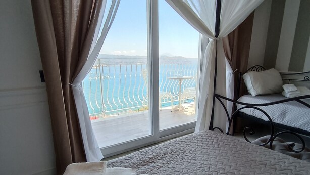 A hotel room with a bed, a view of the sea, and a balcony with a railing. - Relais Tiaré Bed and Breakfast (Bacoli)