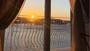 A room with a large window, curtains, a bed, and a view of the sea. - Relais Tiaré Bed and Breakfast (Bacoli)