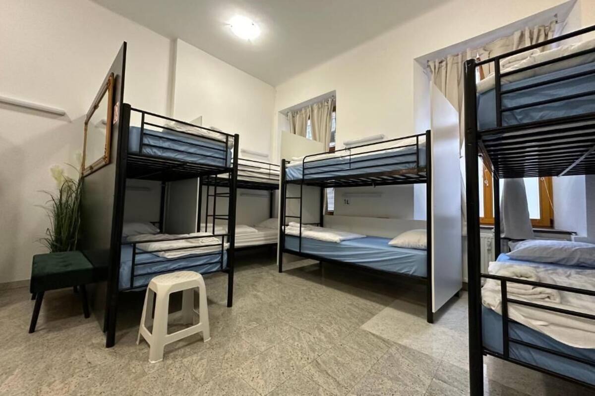 A dormitory room with bunk beds, a small stool, and a mirror.