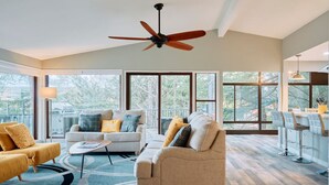 A spacious living room with a high ceiling fan, large windows, and a cozy seating area with a coffee table. - Sedona Retreat:HotTub View Trail (Sedona)