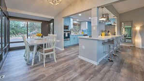 A modern kitchen with a central island, bar stools, and a dining area with a table and chairs. - Sedona Retreat:HotTub View Trail (Sedona)