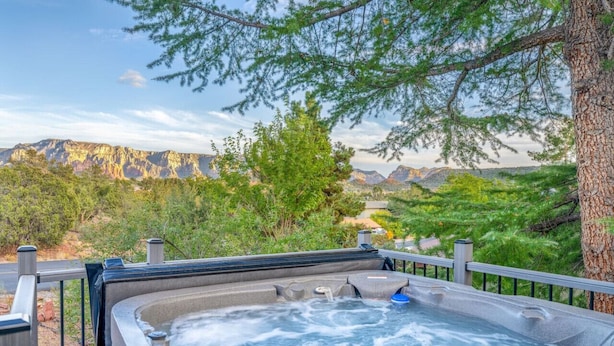 A hot tub with a mountain view, surrounded by trees and a wooden deck. - Sedona Retreat:HotTub View Trail (Sedona)