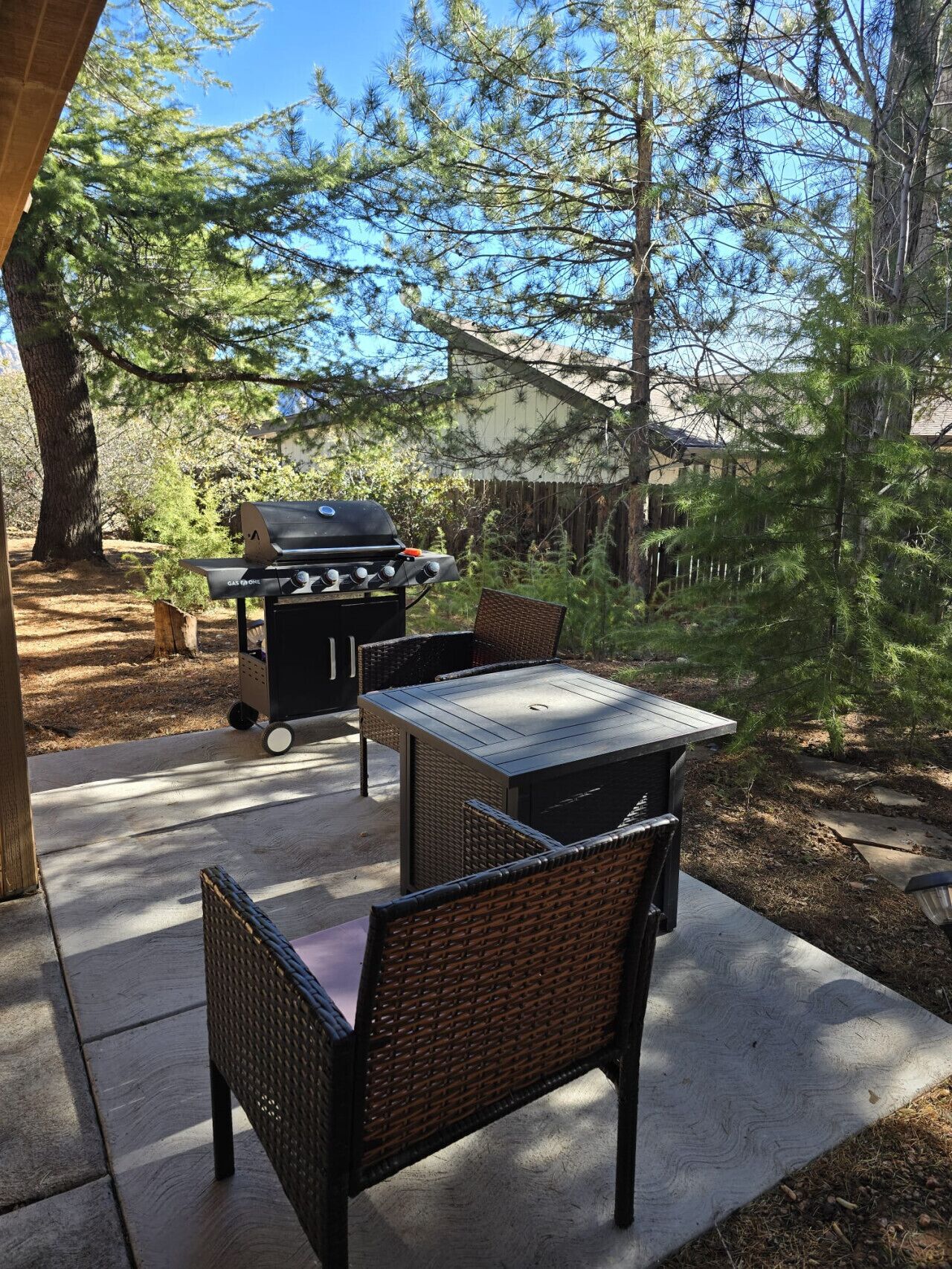 Une terrasse extérieure avec un barbecue, des chaises en osier et une table.