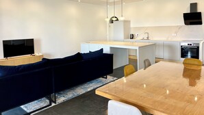 Eine moderne Küche mit weißen Schränken, einem eingebauten Backofen und einem Essbereich mit einem Holztisch und Stühlen.