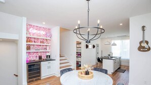 Una cucina moderna con mobili bianchi, un'isola in marmo e un lampadario.