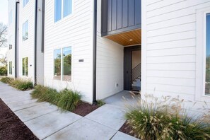 A modern two-story house with a white exterior, a visible number '554', and a front entrance with a staircase.