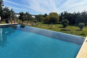 A swimming pool with a clear view of the surrounding landscape, including trees and a distant view of hills.