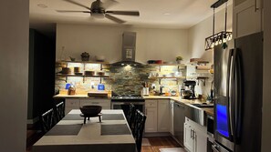 Une cuisine moderne avec un coin repas, équipée d’un réfrigérateur, d’une cuisinière et de divers appareils de cuisine.