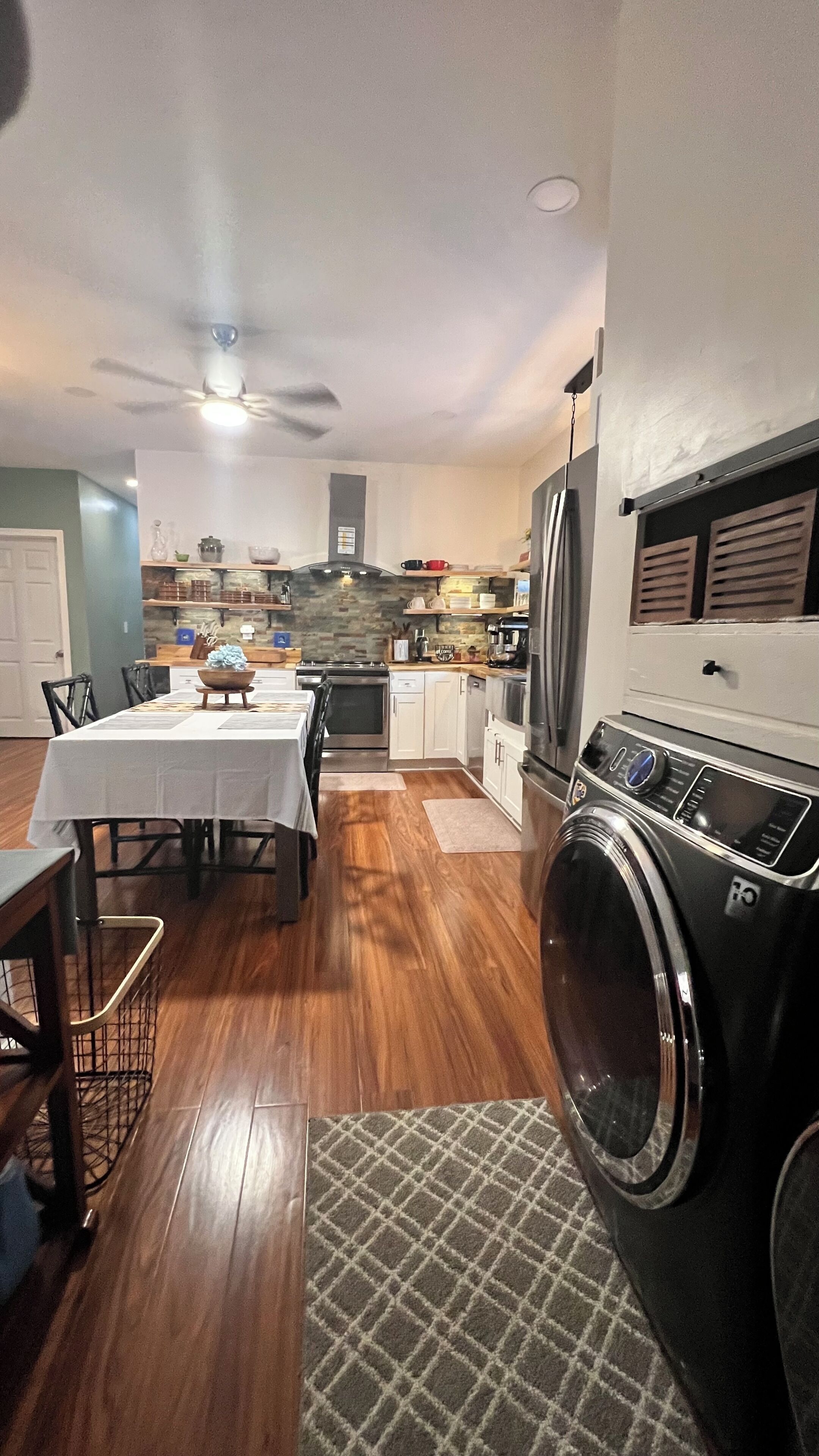A compact kitchen with a dining area, a washing machine, and a ceiling fan.