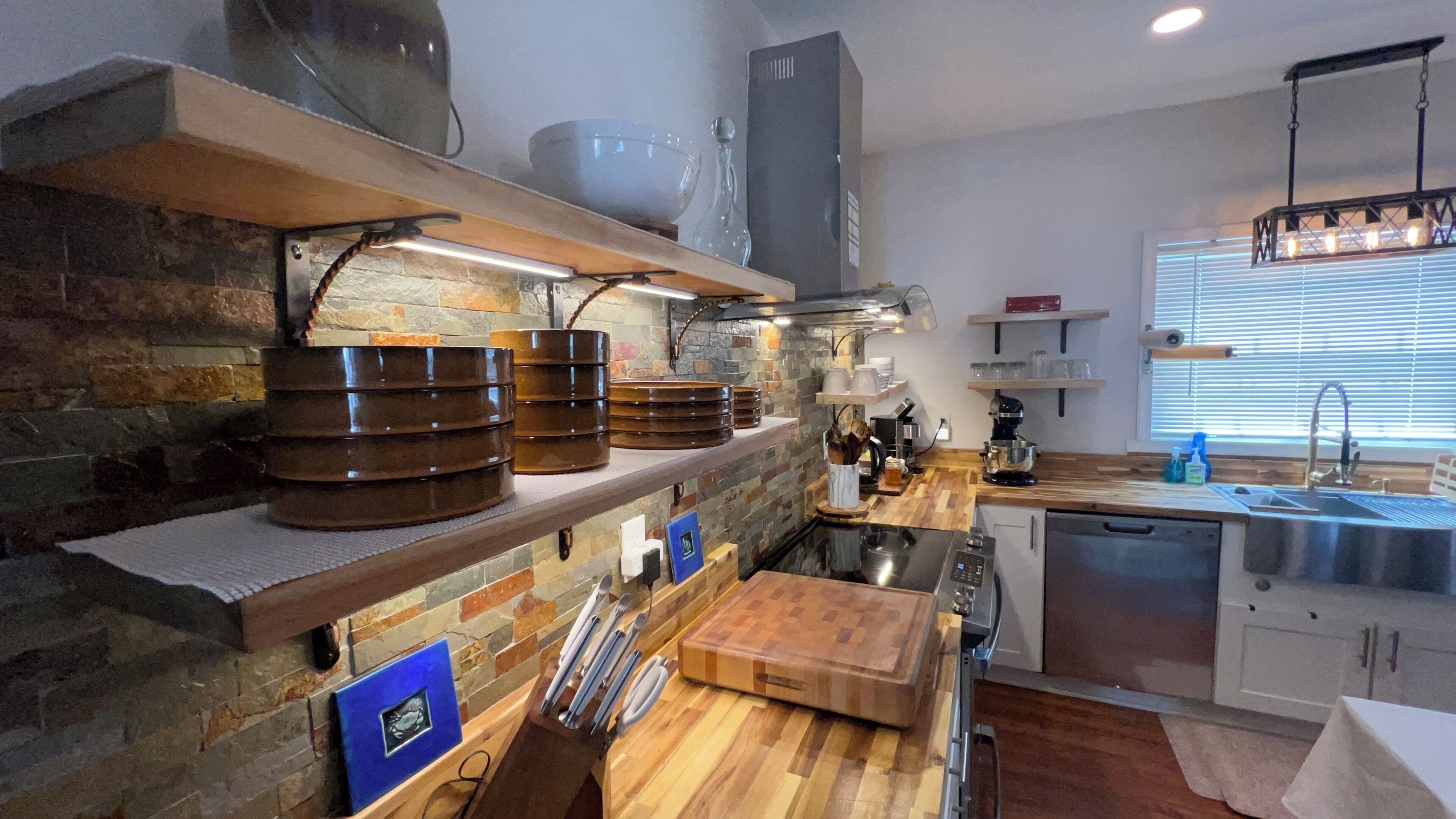A modern kitchen with a stone backsplash, wooden shelves, and a built-in oven.