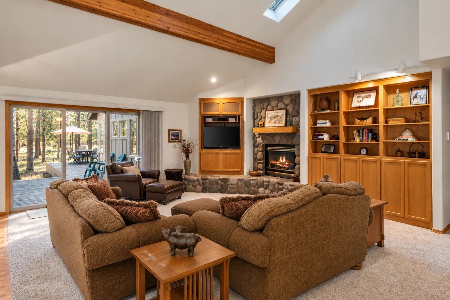 A spacious living room with a fireplace, a television, and a large wooden bookshelf.