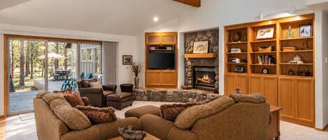 A spacious living room with a fireplace, a television, and a large wooden bookshelf.