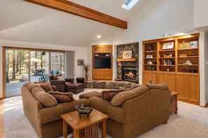 A spacious living room with a fireplace, a television, and a large wooden bookshelf.