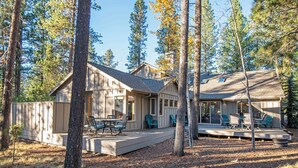 A cabin with a deck, surrounded by tall trees. - Spacious Sunriver retreat w/hot tub + bikes.  Family + Pet Friendly! (Sunriver)