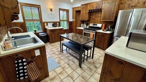Une cuisine avec des armoires en bois, un plan de travail en granit, une cuisinière et un réfrigérateur.