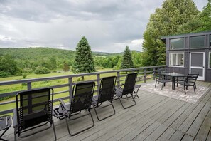Een terras met zitplaatsen buiten en uitzicht op een bebost landschap.